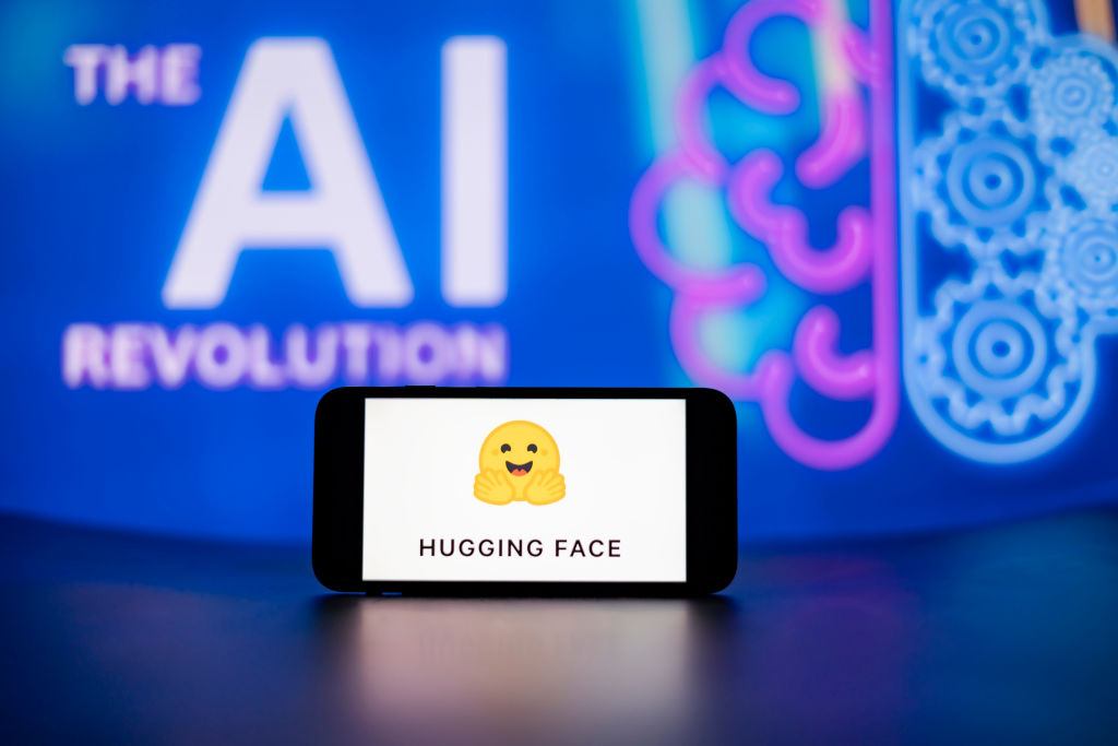 Hugging Faceのロゴを表示したスマートフォンとAIのイメージ